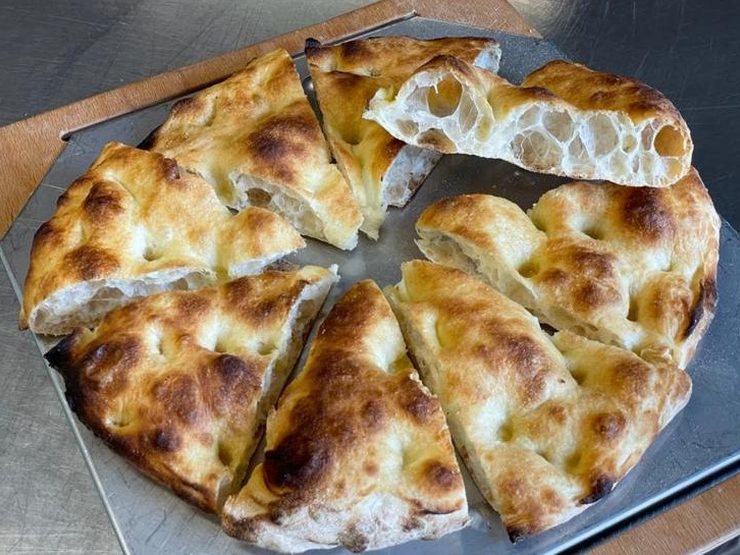 La focaccia scrocchiarella tagliata a spicchi, con l'impasto alveolato in vista